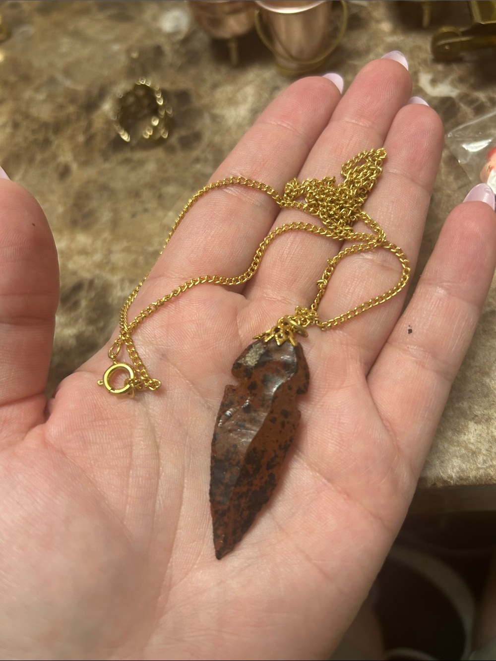 A vintage mahogany obsidian arrowhead pendant on a gold-toned chain